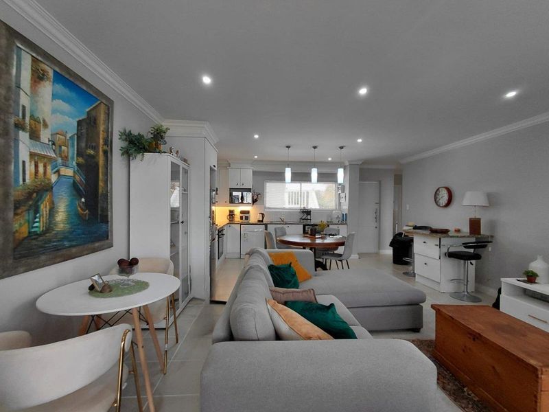 Spacious open-plan living and dining area featuring a modern kitchen with island, recessed lighting, and neutral tiled flooring throughout.