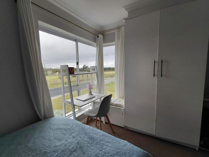 A bright bedroom featuring a built-in wardrobe, crown molding, and a corner window offering pleasant exterior views.