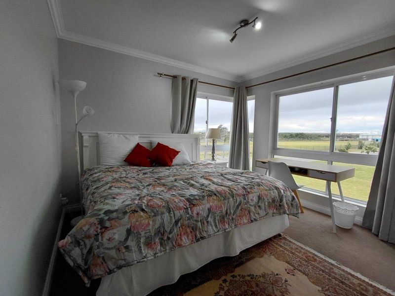A bedroom featuring large sliding windows with natural light, neutral wall finishes, and a ceiling-mounted spotlight fixture.
