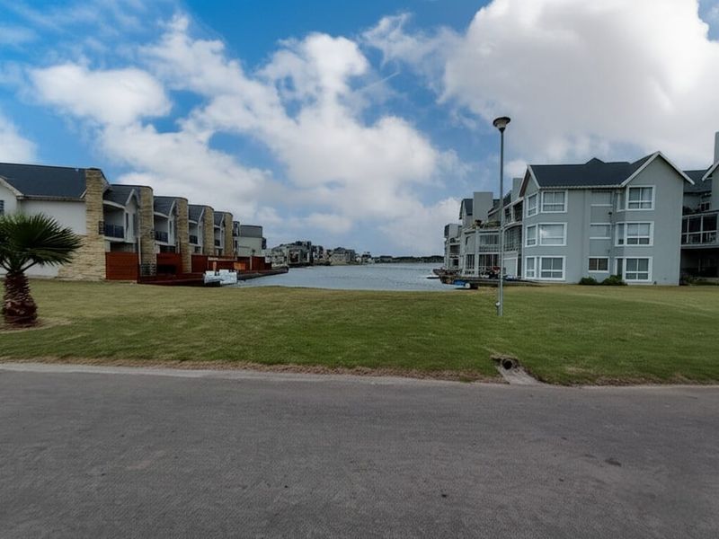 A scenic view of the waterfront residential estate featuring manicured lawns and modern apartment buildings along the canal.