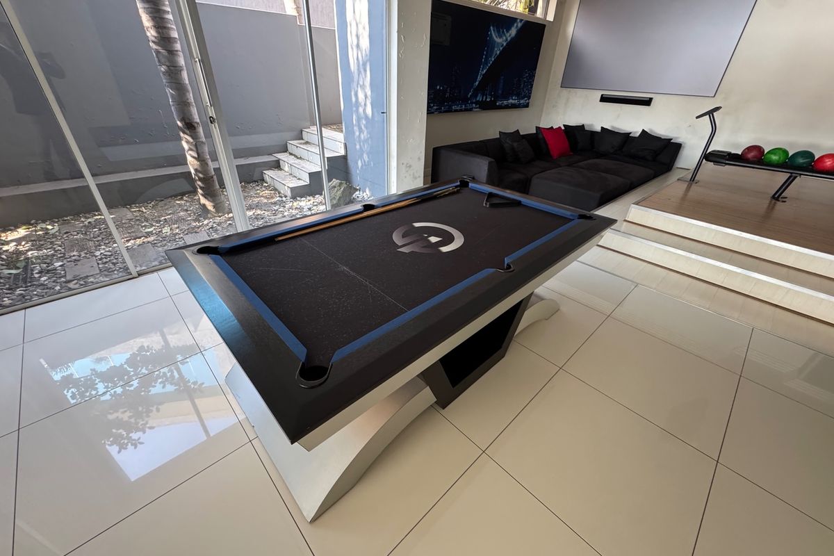 Spacious entertainment room featuring large format floor tiles, sliding glass doors to the exterior, and a raised platform area.