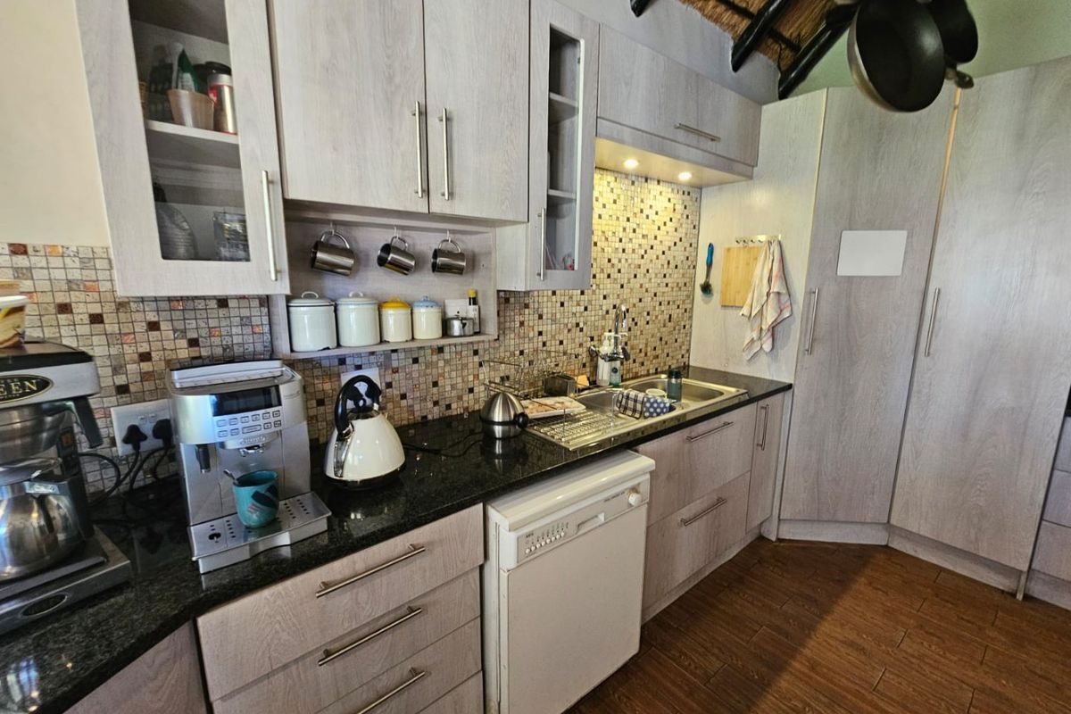 A functional kitchen featuring light wood-grain cabinetry, granite countertops, a mosaic tile backsplash, and a thatched ceiling detail.
