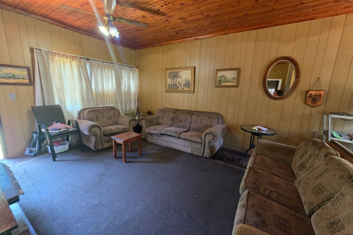 A living room featuring wood-panelled walls and a timber-clad ceiling, offering a dated aesthetic with potential for modernization.