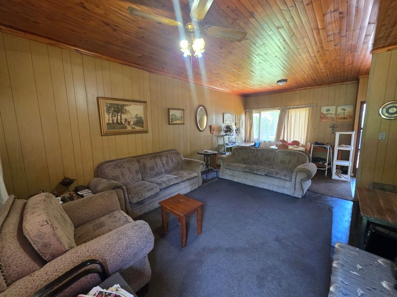 Spacious living area featuring traditional timber wall paneling and a classic tongue and groove timber ceiling with an integrated fan.