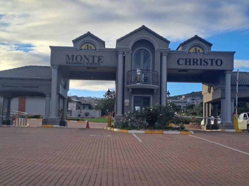 The main entrance gatehouse for the Monte Christo estate, featuring a paved driveway, security boom gates, and a structured architectural facade.