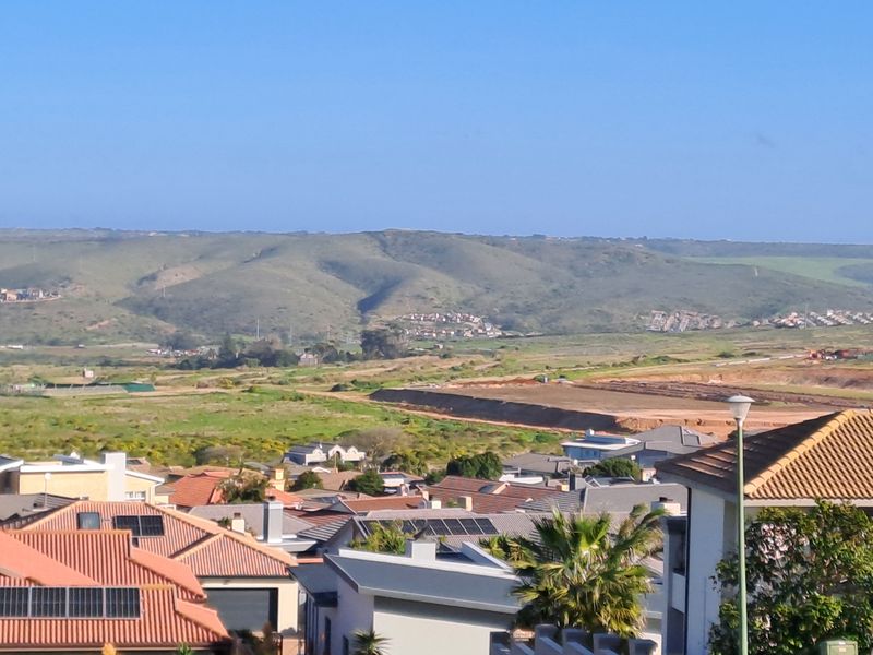 An elevated view overlooking a residential neighborhood with surrounding undeveloped land and distant hills.