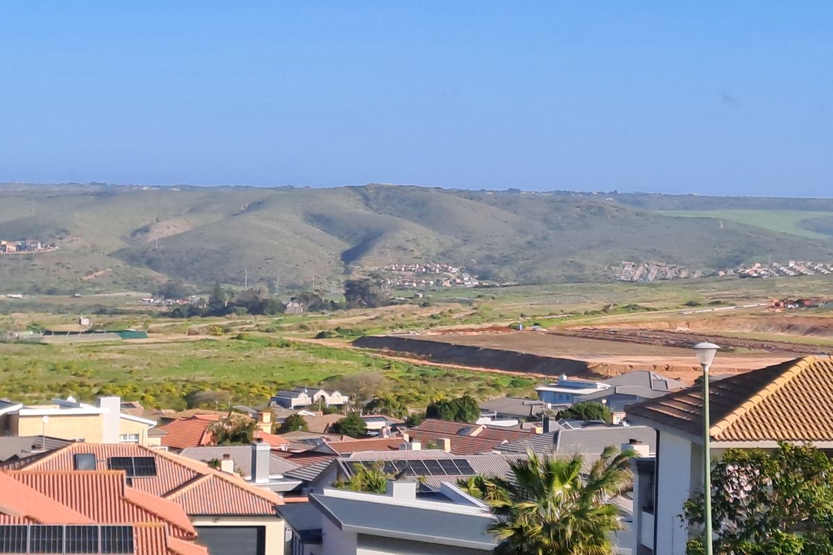 An elevated view overlooking a residential neighborhood with surrounding undeveloped land and distant hills.