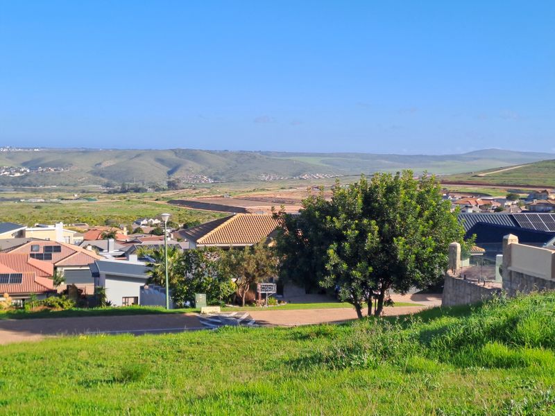 A scenic elevated view overlooking a residential neighborhood and surrounding rolling hills, showcasing the landscape and local development.