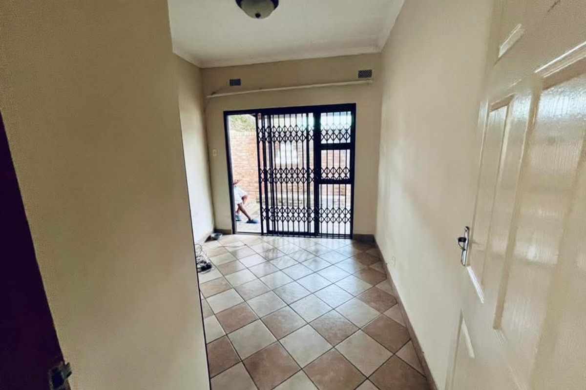 A functional living space featuring tiled flooring and a secure metal sliding door leading to an outdoor area.