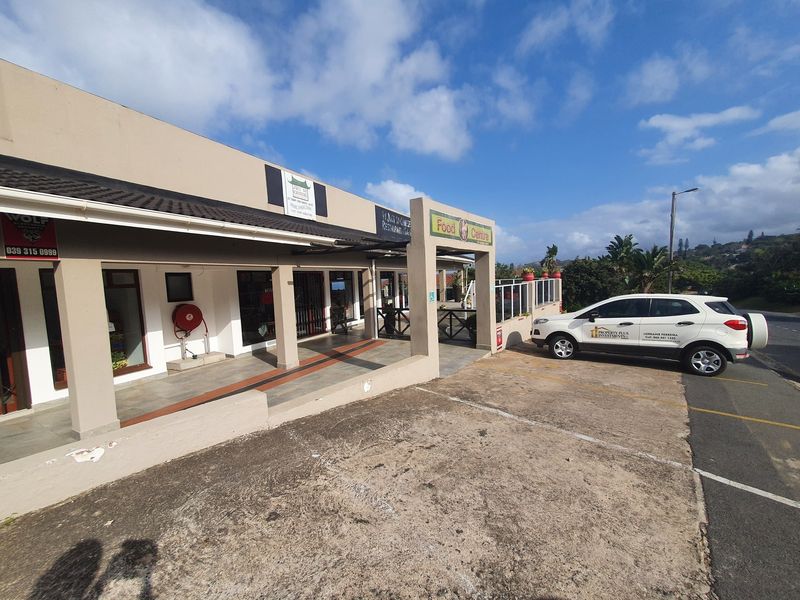 Front exterior view of a commercial food centre featuring a paved parking area, covered walkway, and multiple storefront entrances.