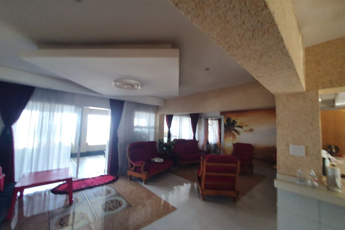Spacious living area featuring a recessed ceiling design, tiled flooring, and large sliding glass doors providing access to the exterior.