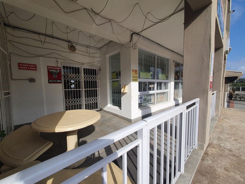 Covered commercial patio area featuring tiled flooring, security gates, and metal railings, suitable for outdoor seating or customer access.