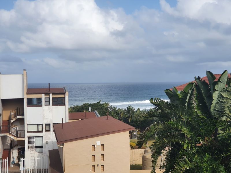 A scenic elevated view overlooking the ocean and surrounding coastal residential buildings.