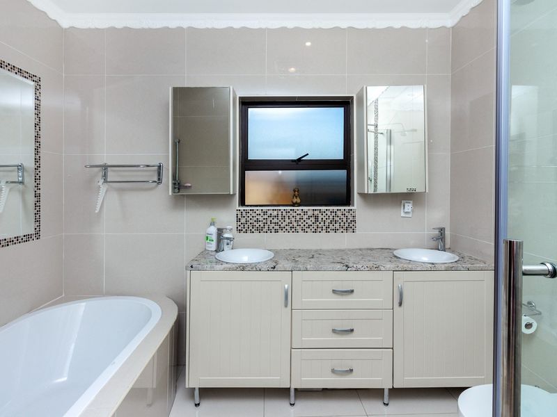Modern bathroom featuring a double vanity with granite countertop, built-in medicine cabinets, a freestanding bathtub, and a separate shower enclosure.