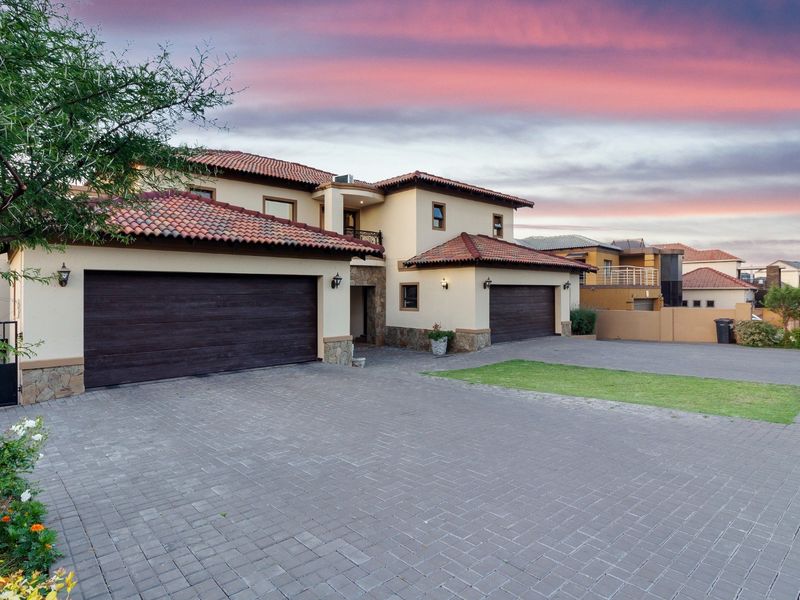 A well-maintained double-story residence featuring a spacious paved driveway, double garage, and attractive stone-clad accents under a classic tiled roof.