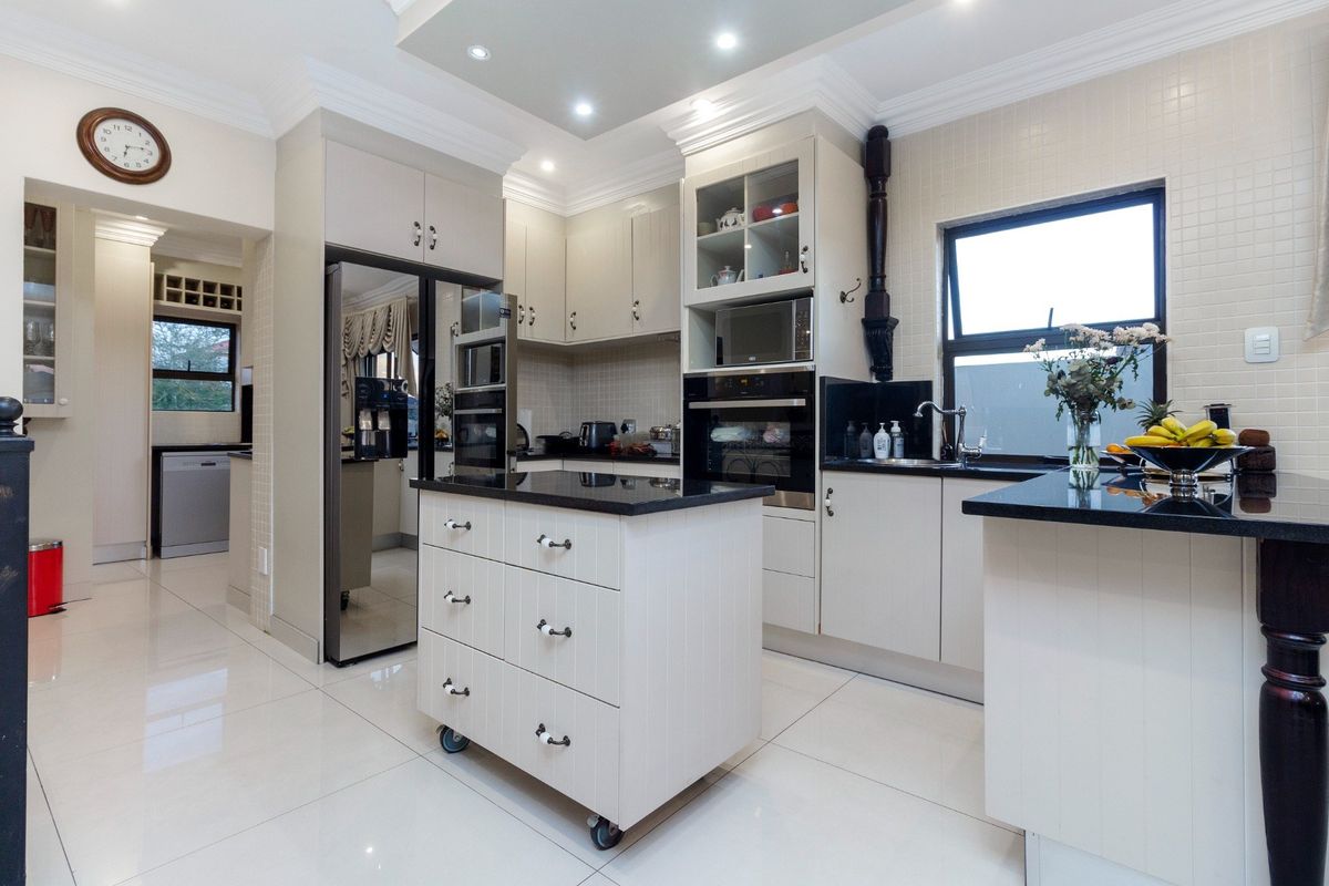 Modern kitchen featuring light-toned cabinetry, granite countertops, built-in appliances, and polished porcelain floor tiles with a central mobile island.