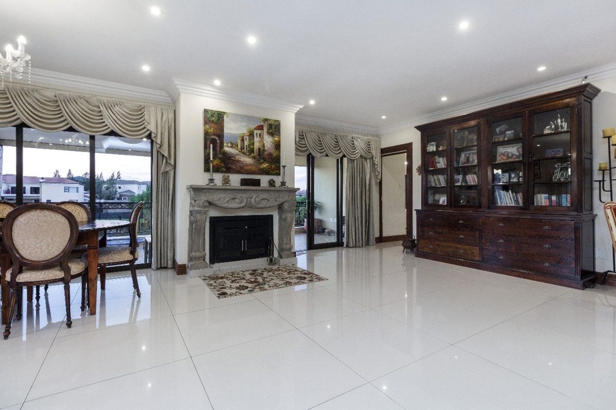 Spacious living room featuring polished porcelain tile flooring, a decorative stone fireplace, and custom built-in cabinetry with integrated lighting.