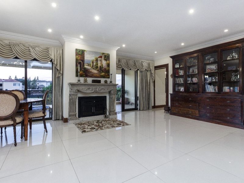 Spacious living room featuring polished porcelain tile flooring, a decorative stone fireplace, and custom built-in cabinetry with integrated lighting.