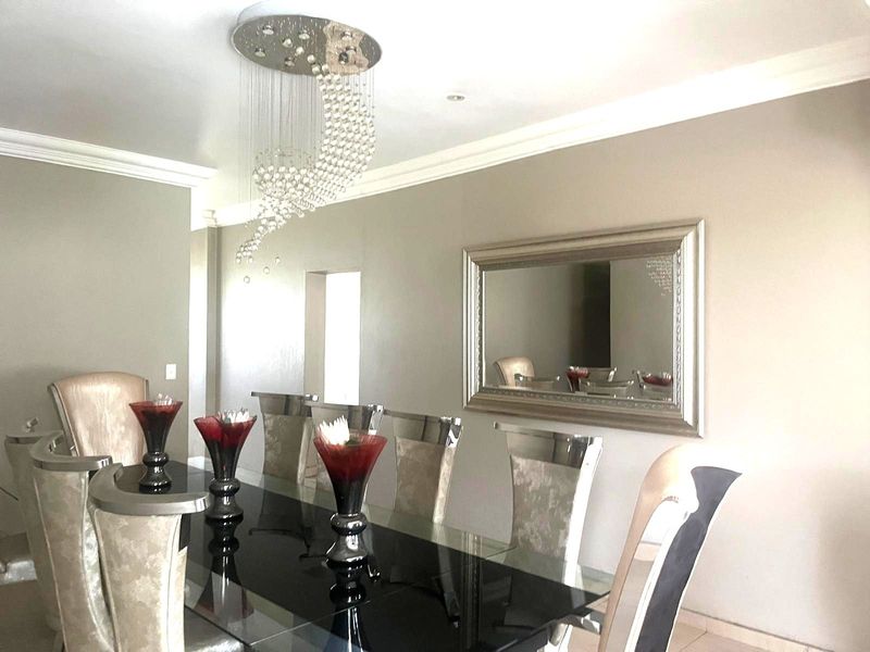 A formal dining room featuring elegant cove cornicing, recessed lighting, and a decorative crystal chandelier, creating a sophisticated atmosphere for entertaining.