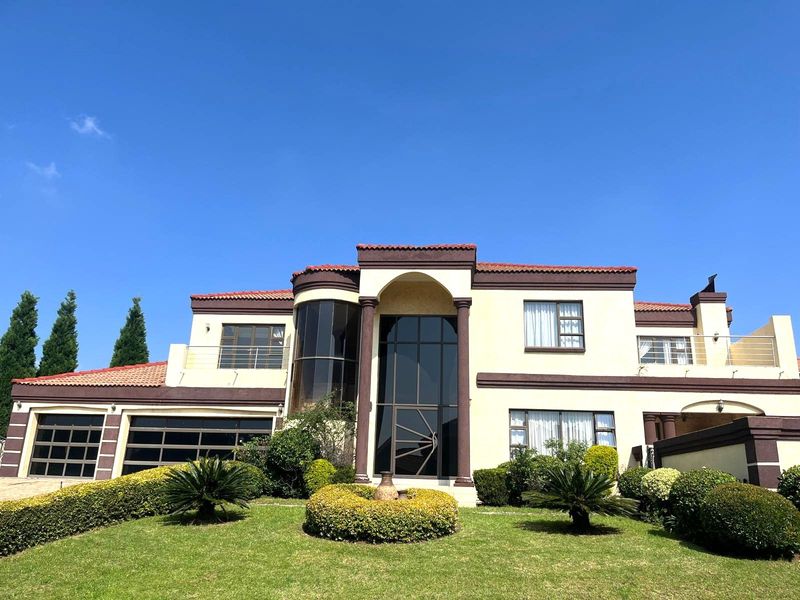 A well-maintained double-story residential property featuring a distinctive curved glass facade, terracotta roof tiles, and a manicured front garden.