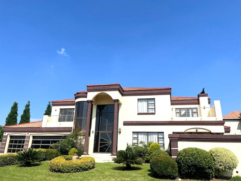 A well-maintained double-story residential property featuring a prominent arched entrance, terracotta roof tiles, a double garage, and a landscaped front garden.