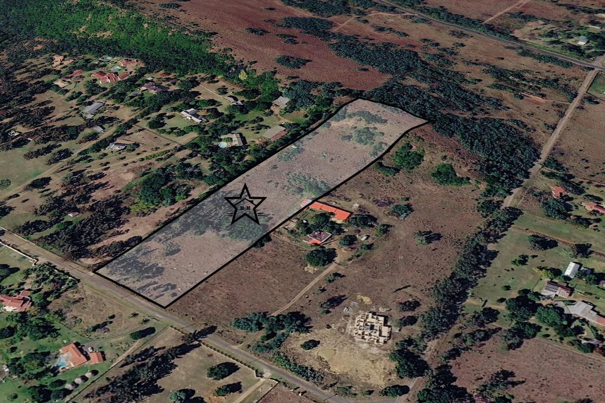 An aerial view of a large, vacant residential plot with boundary lines highlighted, situated in a semi-rural neighborhood setting.