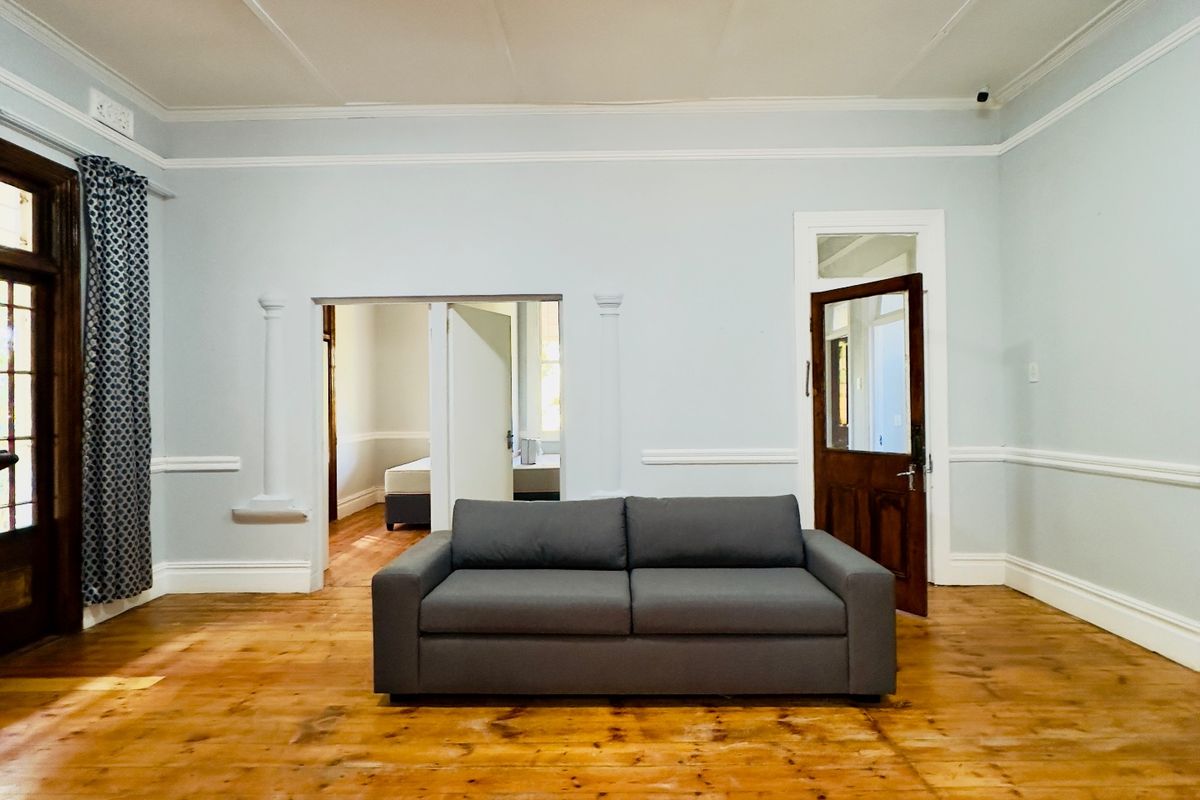 Spacious living room featuring original timber flooring, crown molding, and chair rail detailing, offering a classic foundation for modern interior design.