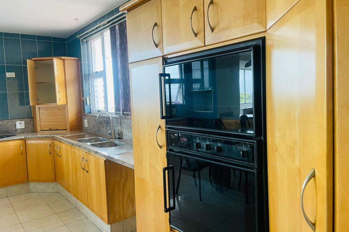 A functional kitchen featuring light wood cabinetry, granite countertops, a double sink, and a built-in oven with a tiled splashback.