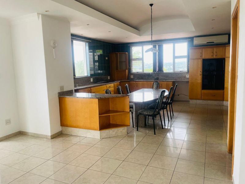 Spacious open-plan kitchen and dining area featuring granite countertops, ample wooden cabinetry, tiled flooring, and integrated appliances.