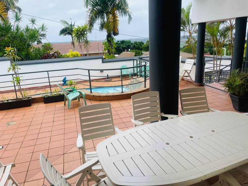 Spacious covered patio featuring tiled flooring, structural columns, and a raised pool, offering an ideal outdoor entertainment area with neighbourhood views.