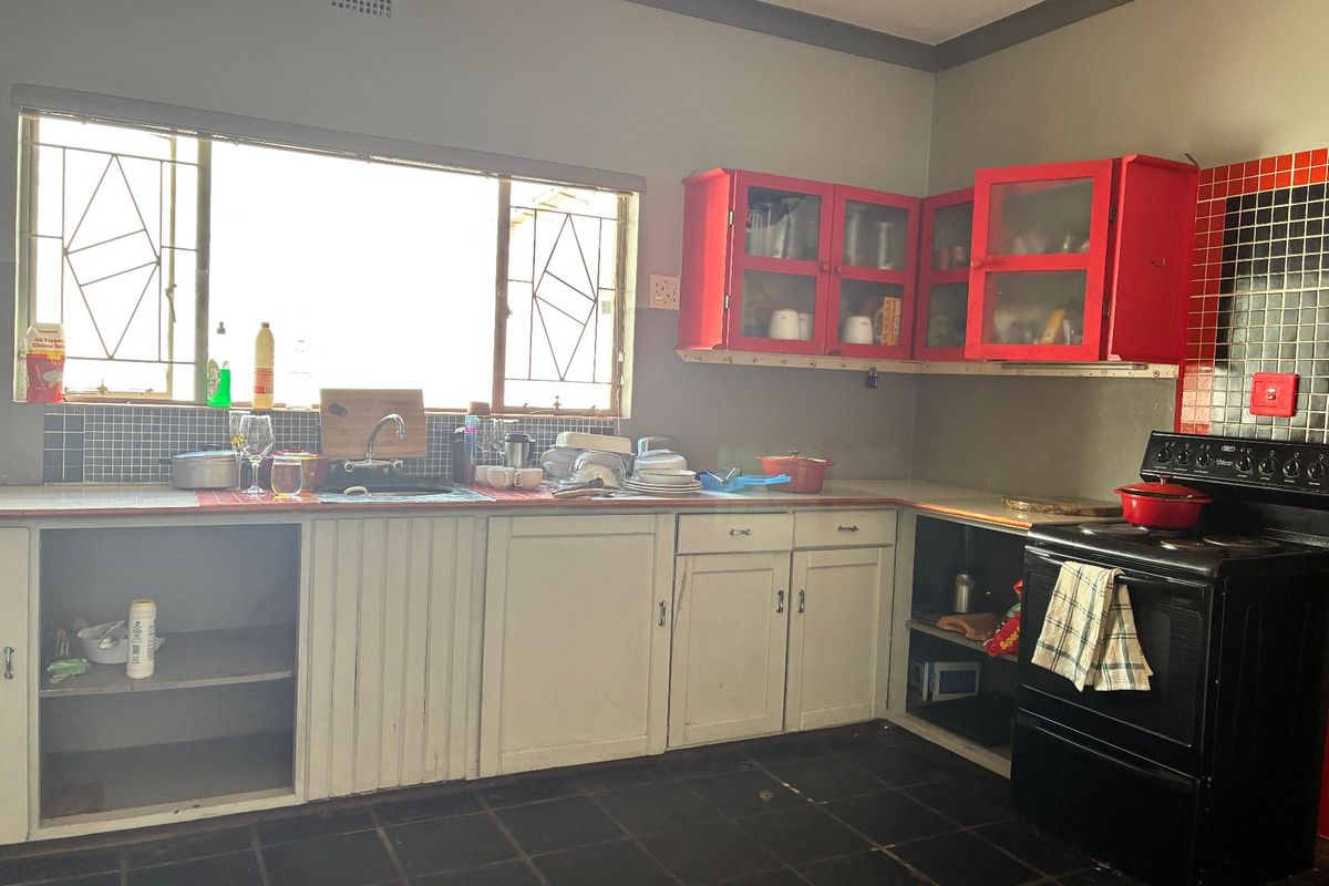 A dated kitchen featuring original cabinetry, tiled splashbacks, and a freestanding stove, offering significant potential for modernization and renovation.