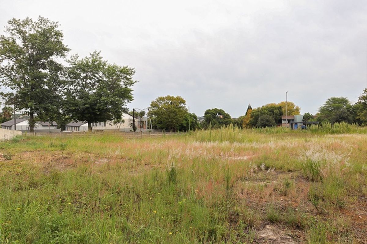 A vacant residential plot featuring natural grass cover and perimeter fencing, offering a clear space for future development.