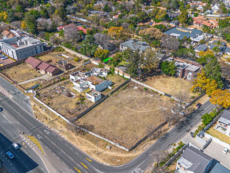 Aerial view of a vacant residential plot featuring perimeter walling and boundary fencing, situated in a developed suburban neighborhood.
