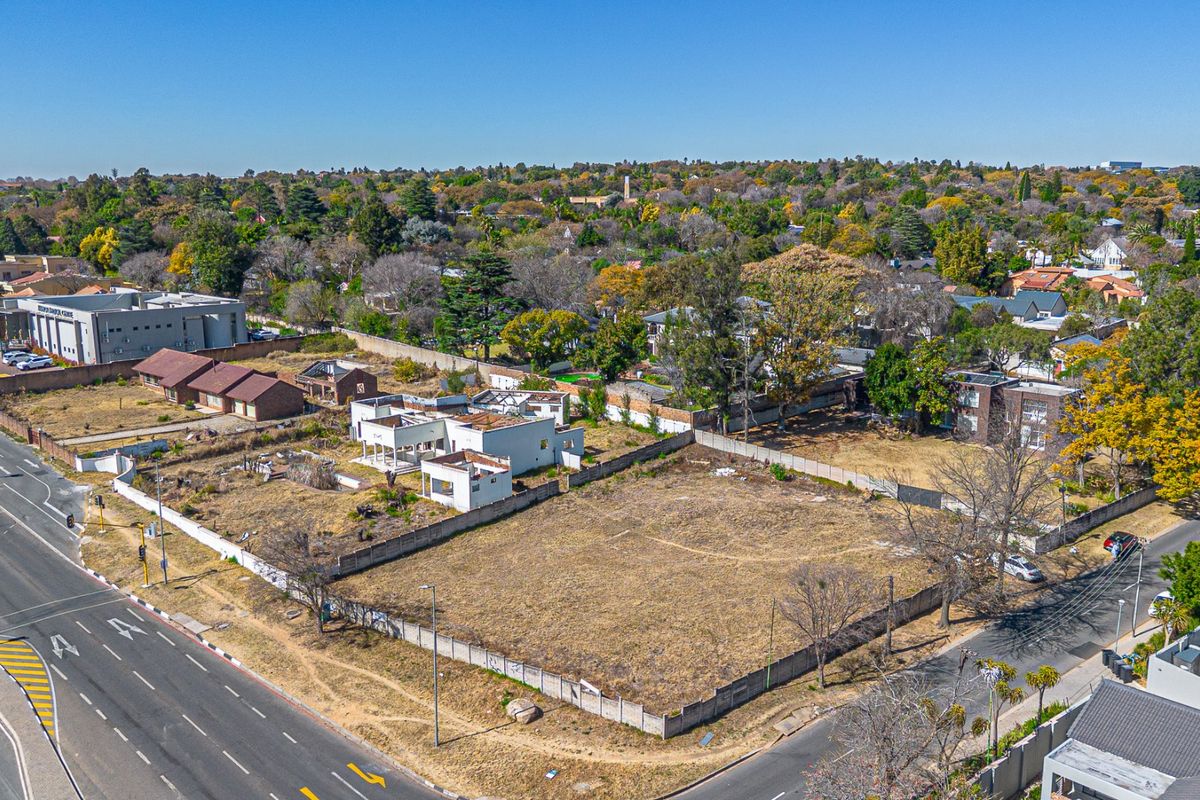 Aerial view of a vacant residential land parcel featuring perimeter walling and an existing dilapidated structure, situated in a developed urban area.