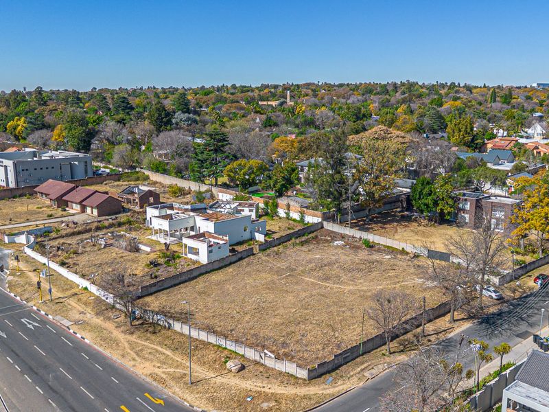 Aerial view of a vacant residential land parcel featuring perimeter walling and an existing dilapidated structure, situated in a developed urban area.