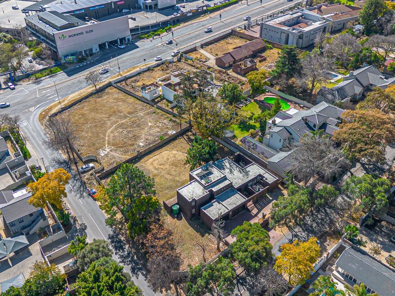 Aerial view of a residential vacant land plot situated in a developed urban area with established boundary walls and mature trees.
