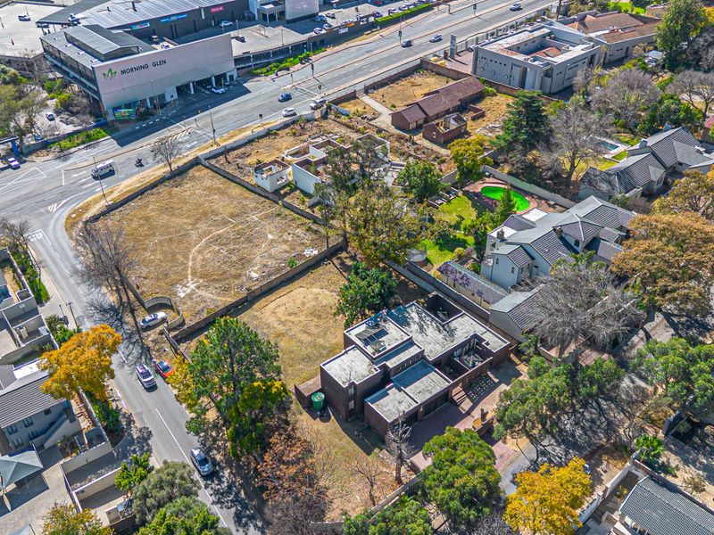 Aerial view of a residential vacant land plot situated in a developed suburban area near commercial facilities.