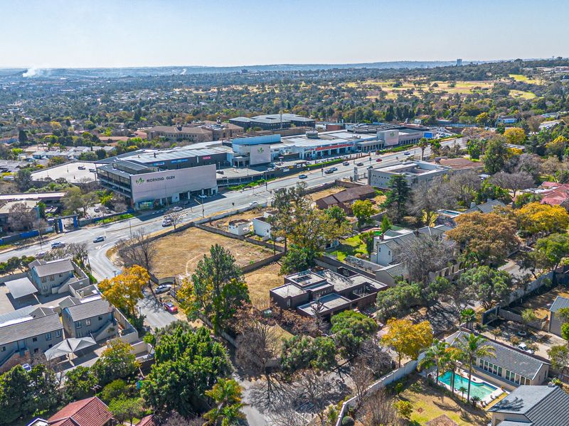 Aerial view of a vacant residential land plot situated in a developed suburban area near a shopping center.