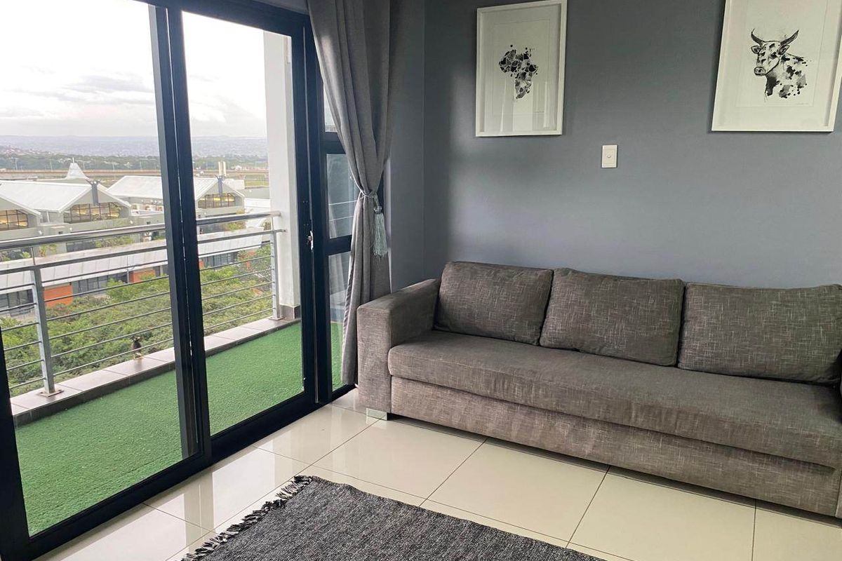 A modern living room featuring large sliding glass doors that open onto a balcony, providing natural light and outdoor access.