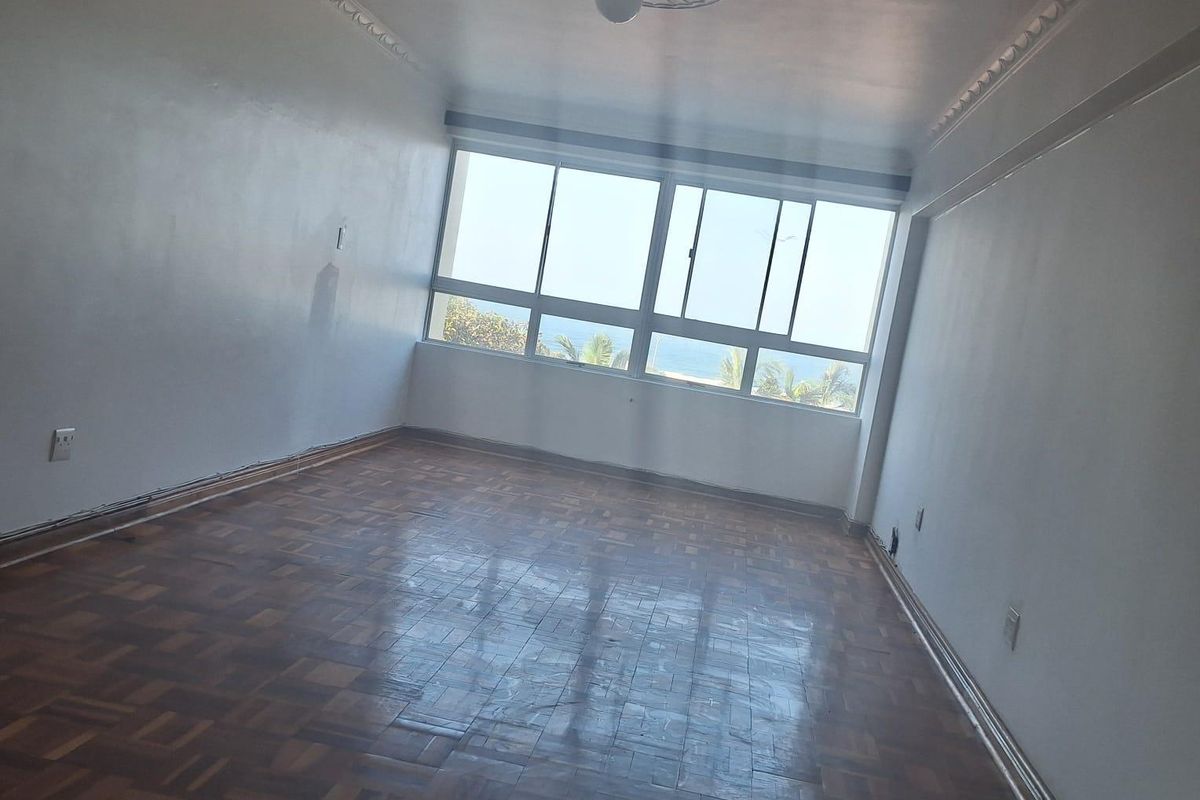 An empty living room featuring classic parquet flooring, decorative ceiling cornicing, and a large window offering natural light and a view.