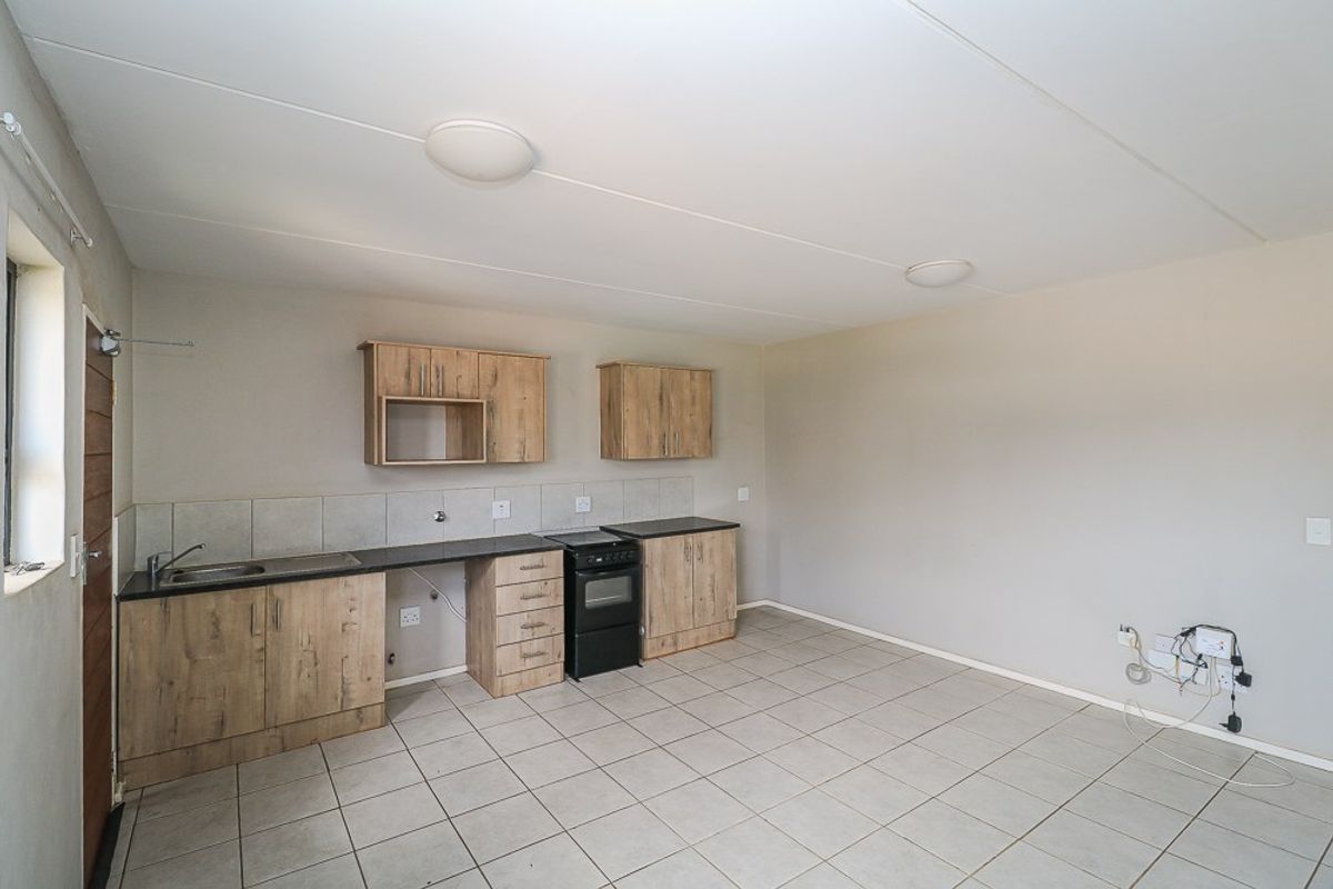 A functional kitchen featuring light wood-look cabinetry, tiled flooring, a built-in oven, and a tiled backsplash, offering a clean and practical workspace.
