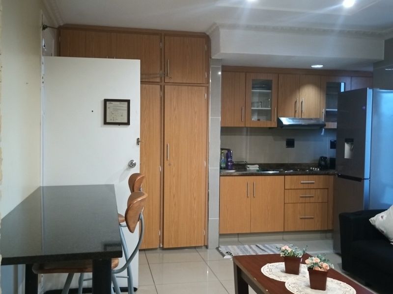 Open plan living and kitchen area featuring wood-finish cabinetry, tiled flooring, and integrated kitchen fixtures in a functional layout.