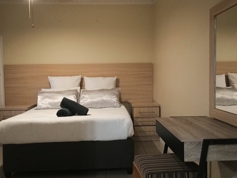 A functional bedroom featuring tiled flooring, a ceiling fan, and built-in headboard with integrated bedside cabinetry.