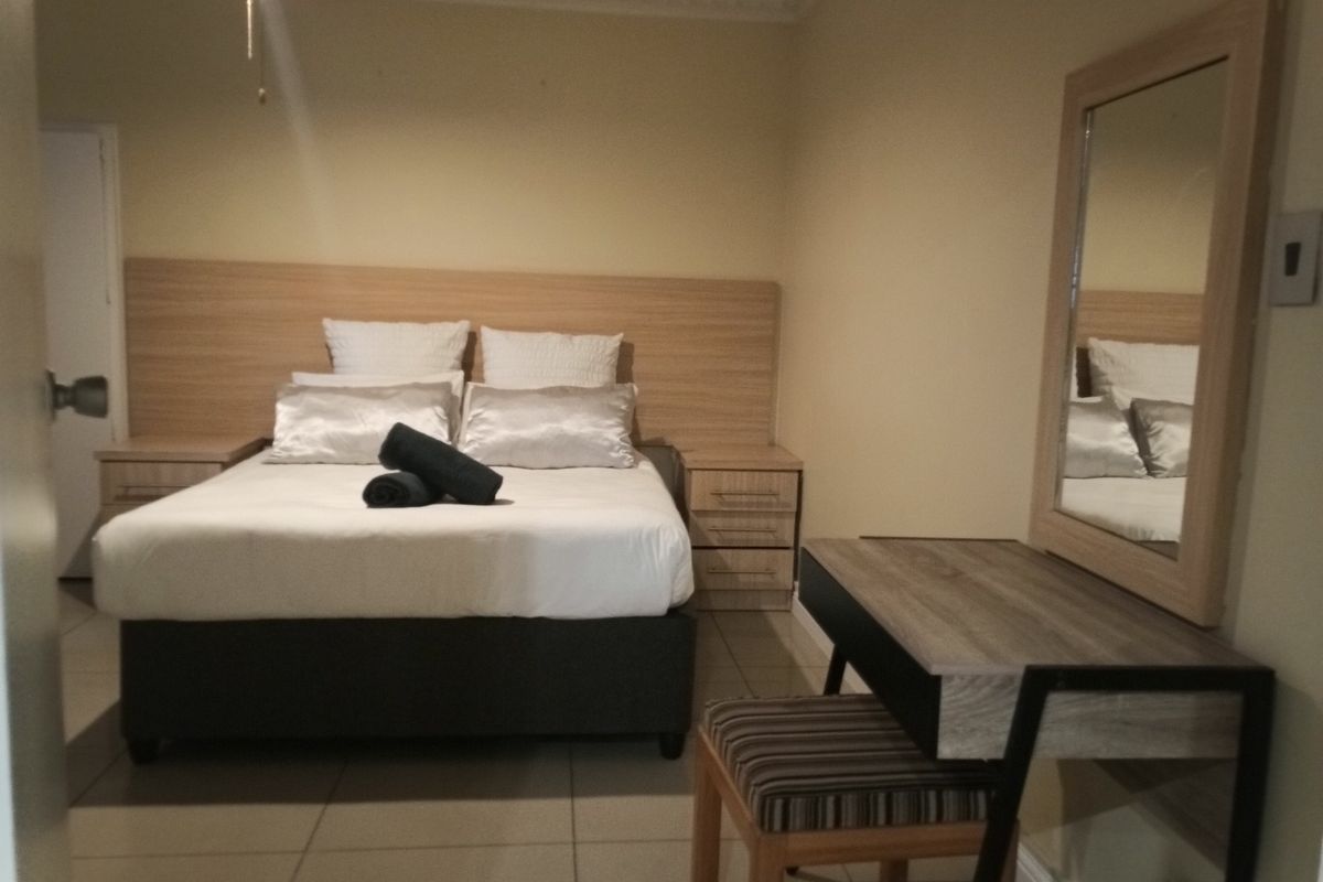 A bedroom featuring a built-in headboard and tiled flooring, providing a functional and neutral space.