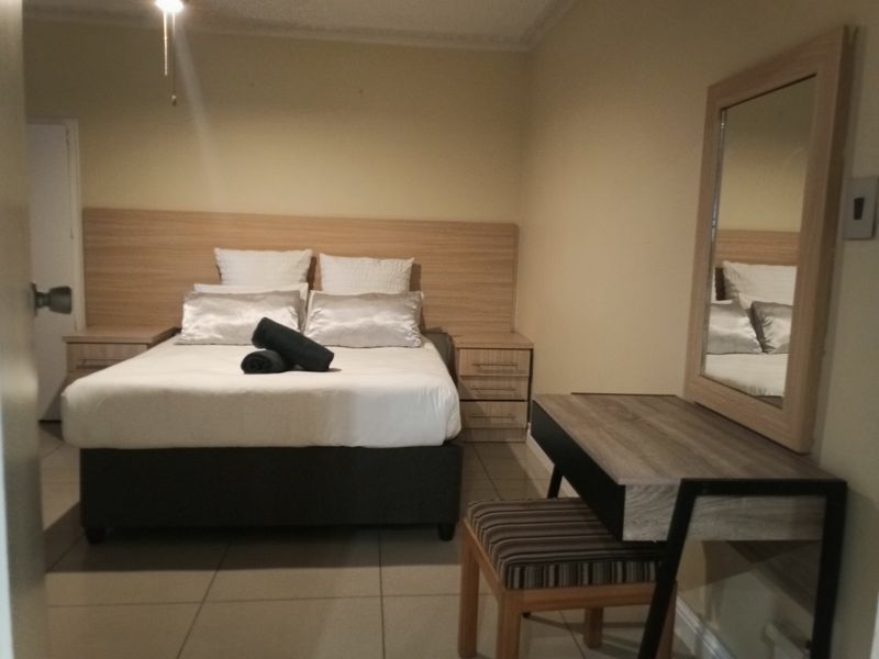 A bedroom featuring a built-in headboard and tiled flooring, providing a functional and neutral space.