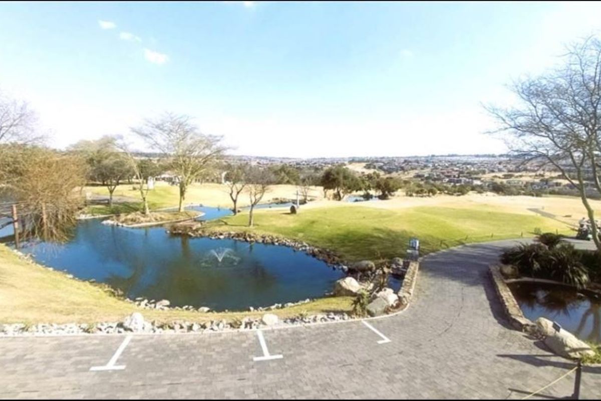 A scenic elevated view overlooking a landscaped pond, golf course grounds, and surrounding residential estate landscape.