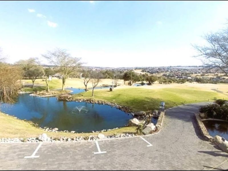 A scenic elevated view overlooking a landscaped pond, golf course grounds, and surrounding residential estate landscape.