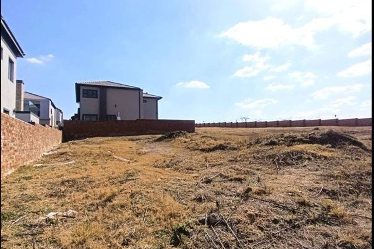 A vacant residential plot featuring established brick boundary walls and surrounding residential development.