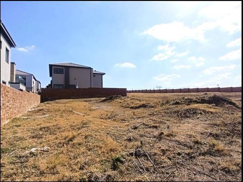 A vacant residential plot featuring established brick boundary walls and surrounding residential development.