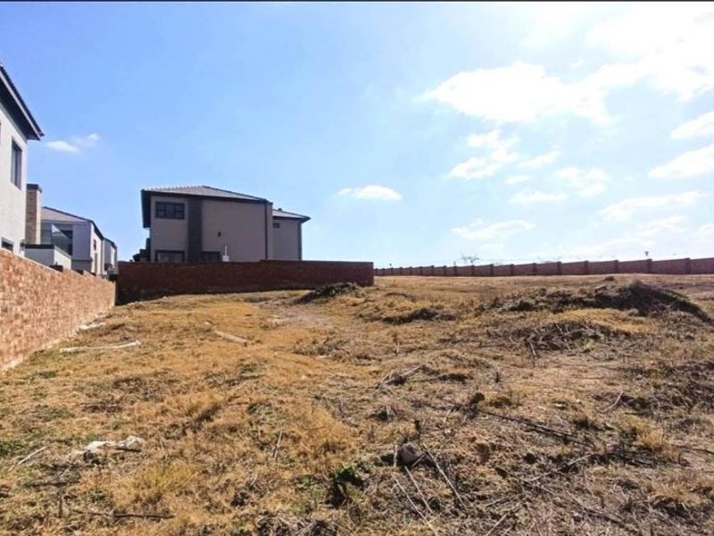A view of the vacant residential land featuring a brick boundary wall and adjacent residential structures.